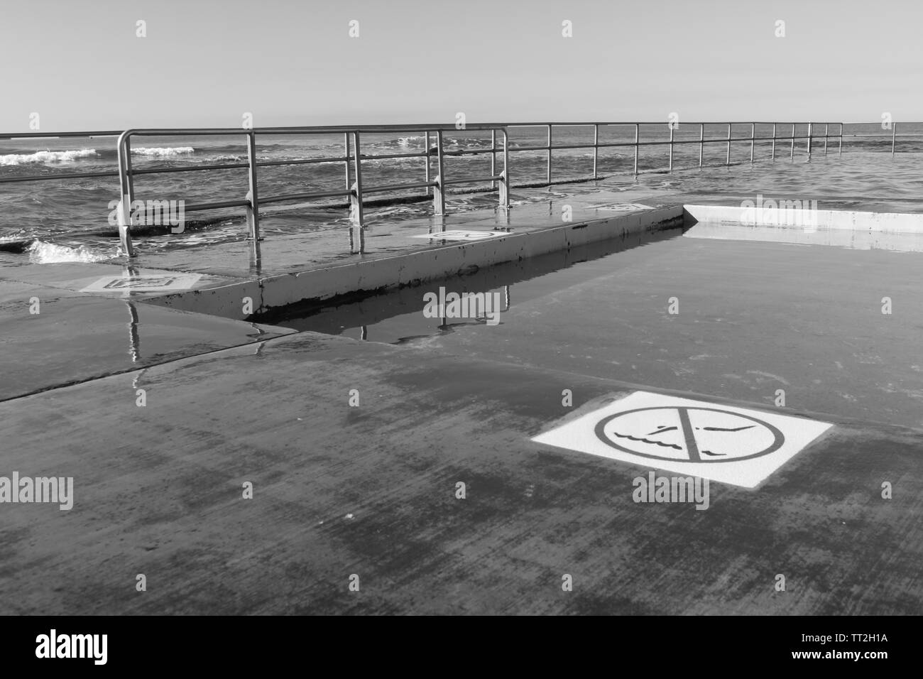 Monocromatico roccia mare piscina con nessun segno di immersioni e parapetti Foto Stock