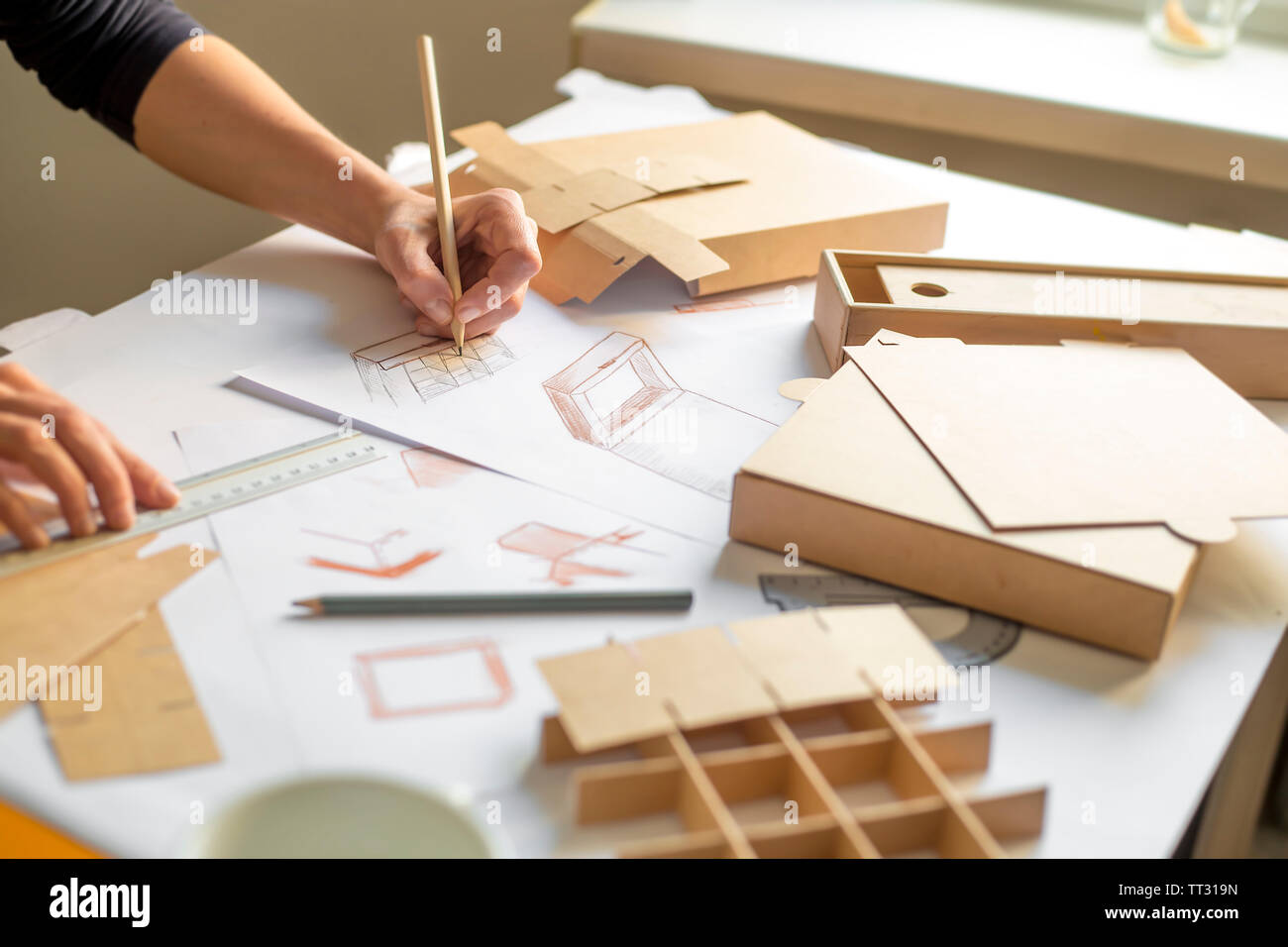 Designer disegna un mockup per la creazione di una scatola di cartone. Sviluppo di packaging design sketch. Foto Stock