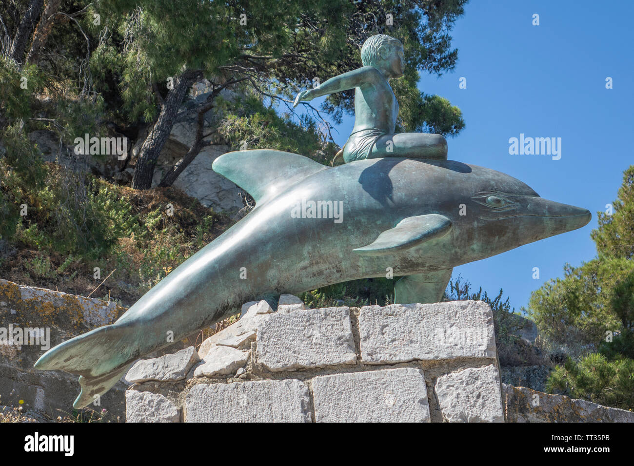 Grecia Isole Saroniche, Hydra, ragazzo sulla scultura dei delfini Foto Stock