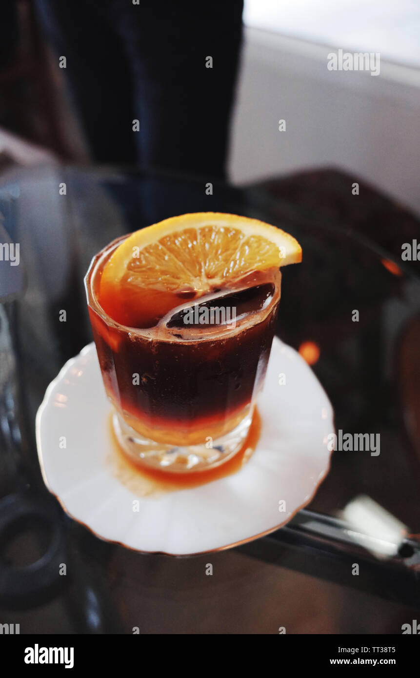Bicchiere pieno di caffè ghiacciato su una tabella con la fetta di arancia. Foto Stock