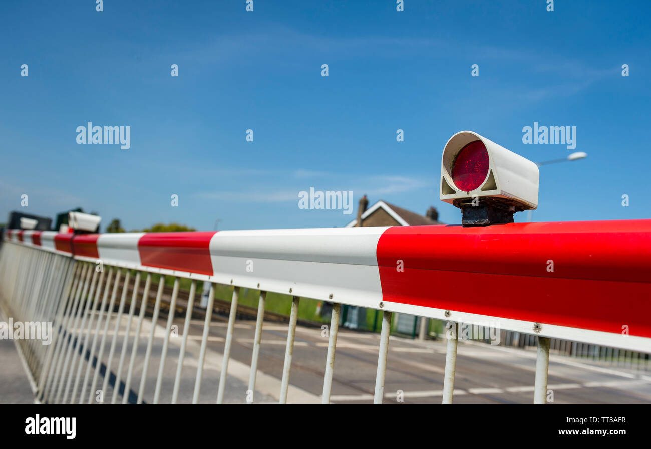 Barriere di sicurezza nella posizione di chiusura attraverso un passaggio a livello ferroviario nel Regno Unito. Foto Stock