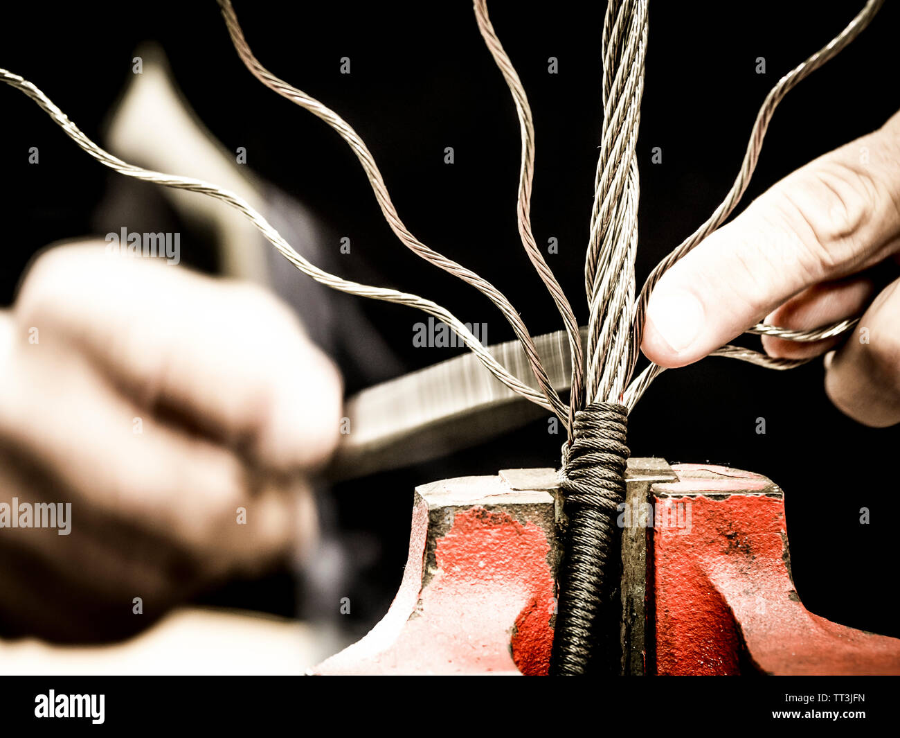 Mani lavorando un cavo in acciaio Foto Stock