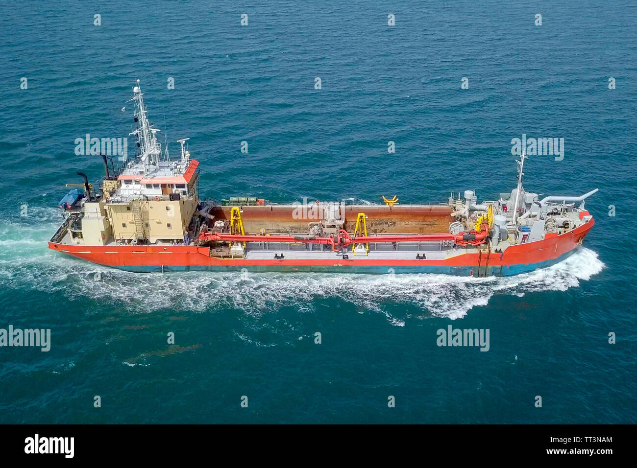 Rosso di aspirazione finale Hopper-Dredger nave ruggente attraverso il mare, immagine aerea. Foto Stock