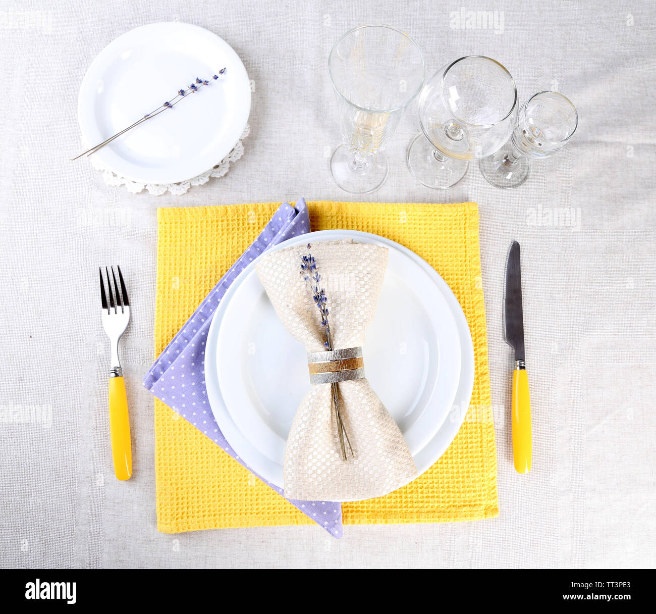 Tavolo da pranzo impostazione con fiori di lavanda sulla tovaglia di luce sullo sfondo Foto Stock
