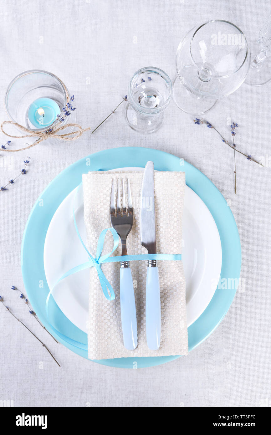 Tavolo da pranzo impostazione con fiori di lavanda sulla tovaglia di luce sullo sfondo Foto Stock