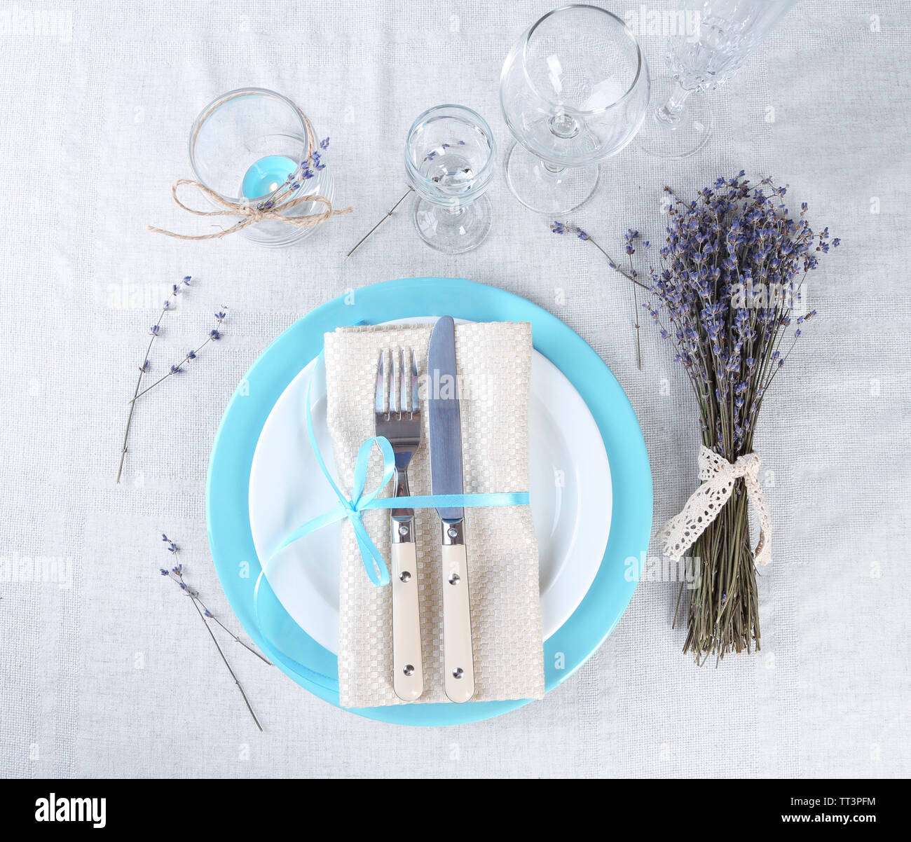Tavolo da pranzo impostazione con fiori di lavanda sulla tovaglia di luce sullo sfondo Foto Stock