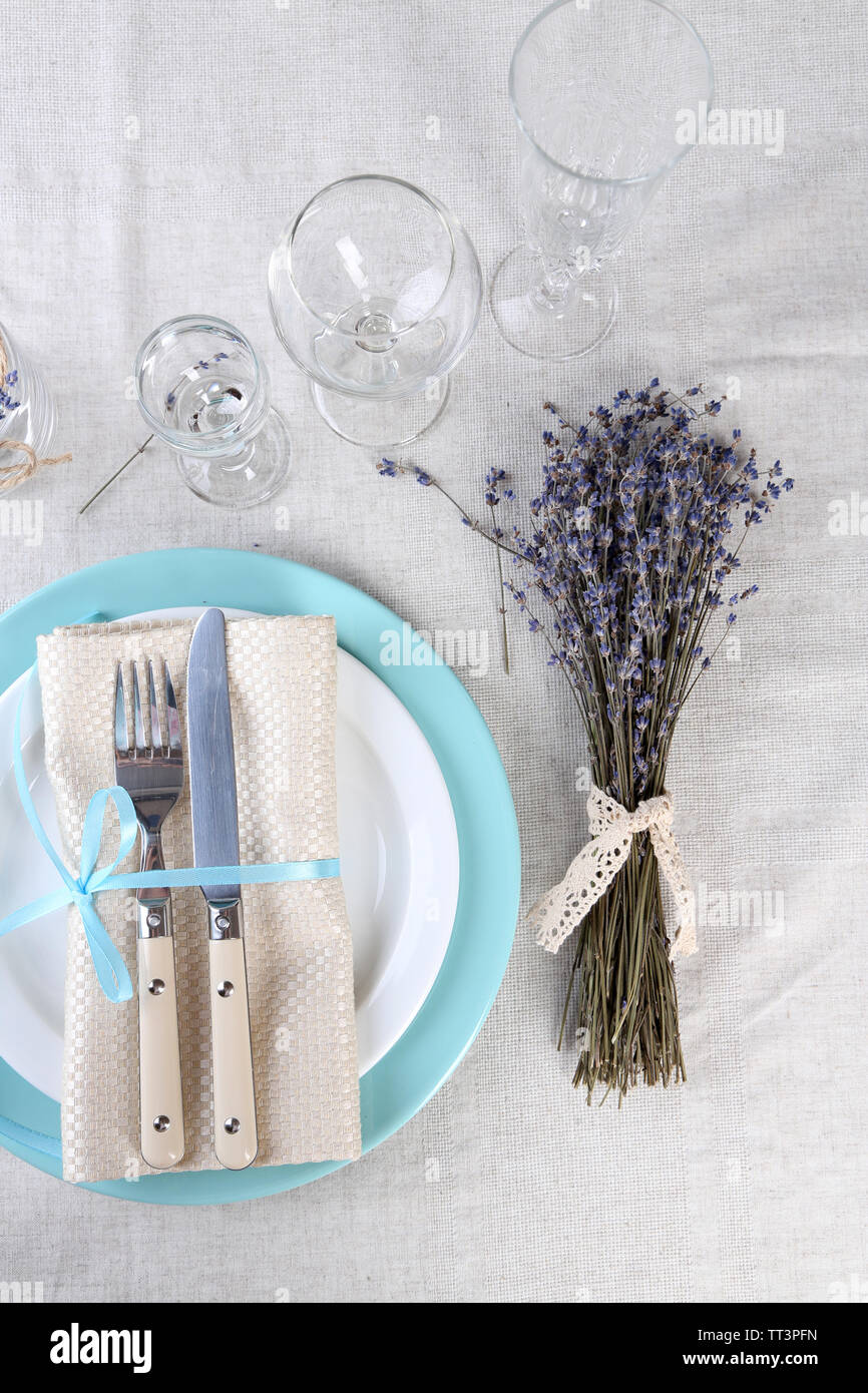 Tavolo da pranzo impostazione con fiori di lavanda sulla tovaglia di luce sullo sfondo Foto Stock