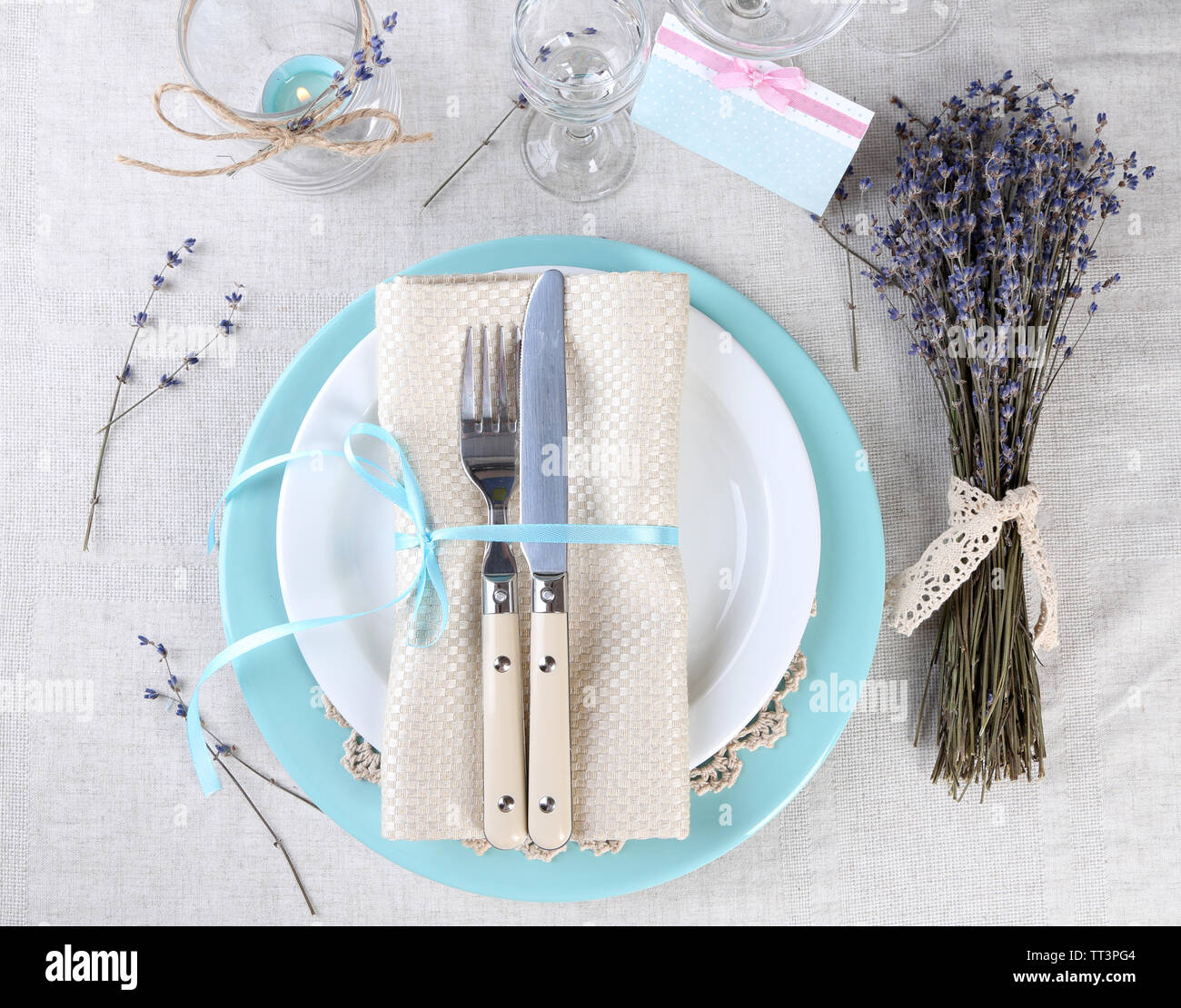 Tavolo da pranzo impostazione con fiori di lavanda sulla tovaglia di luce sullo sfondo Foto Stock