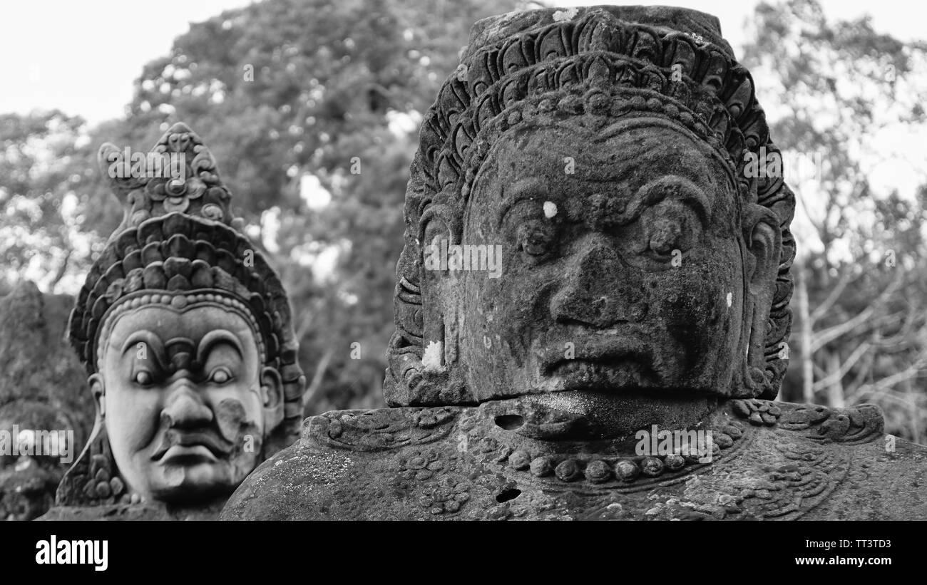 Due rovinato volto arrabbiato statue sulla strada al di fuori della antica città dell'Impero Khmer - Angkor Thom. (Angkor Wat, Siem Reap, Cambogia) Foto Stock