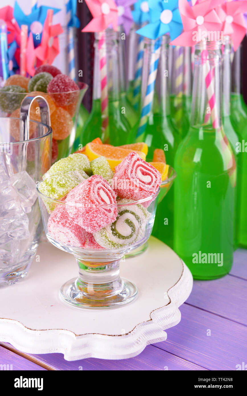 Bottiglie con bevande e caramelle sul tavolo vicino fino Foto Stock
