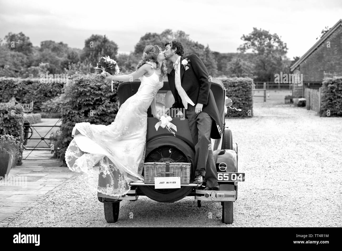 Sposa e lo Sposo kiss mentre in piedi su un'auto d'Epoca Foto Stock