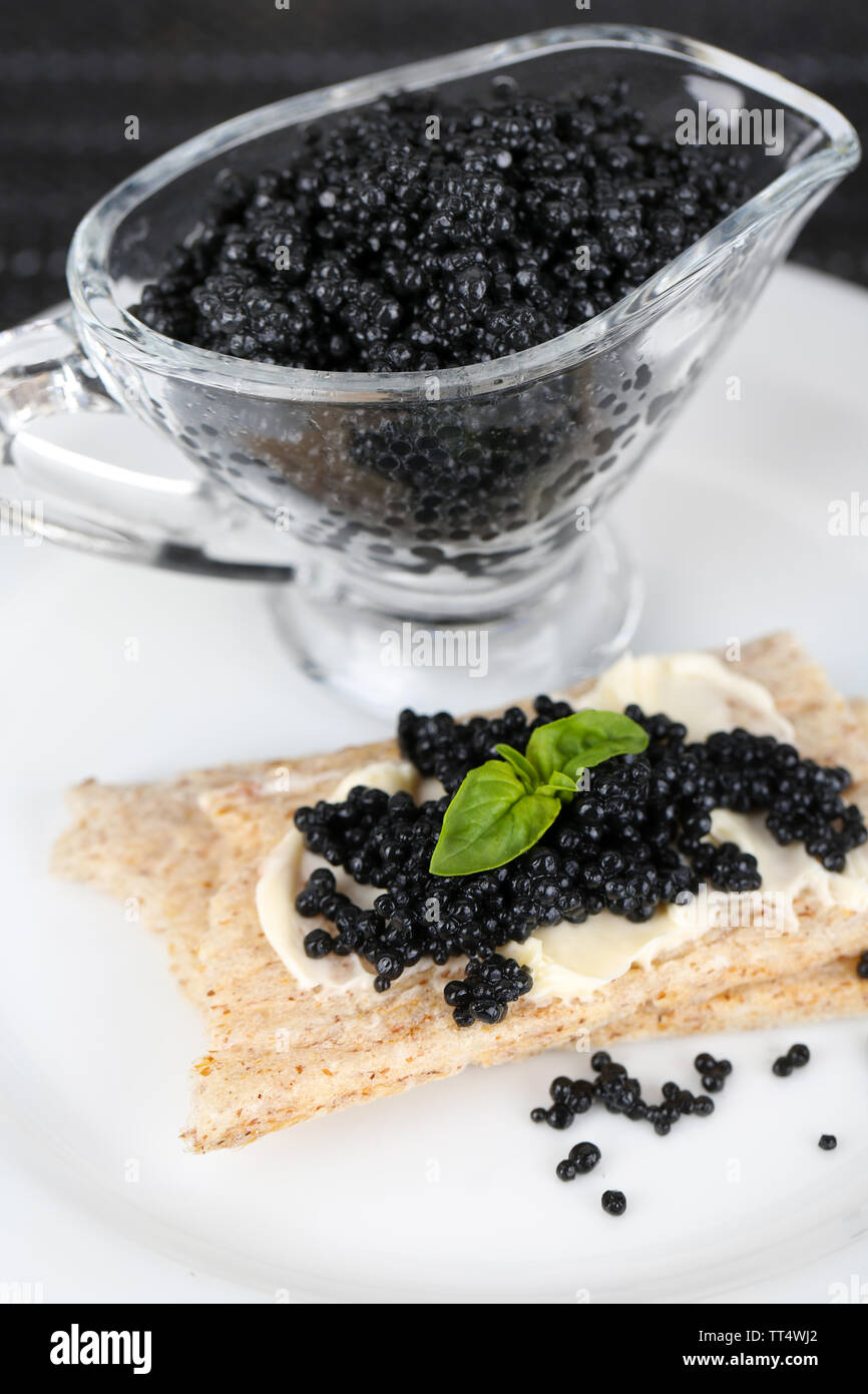 Fetta di pane con burro e sauceboat con caviale su piastra in primo piano Foto Stock