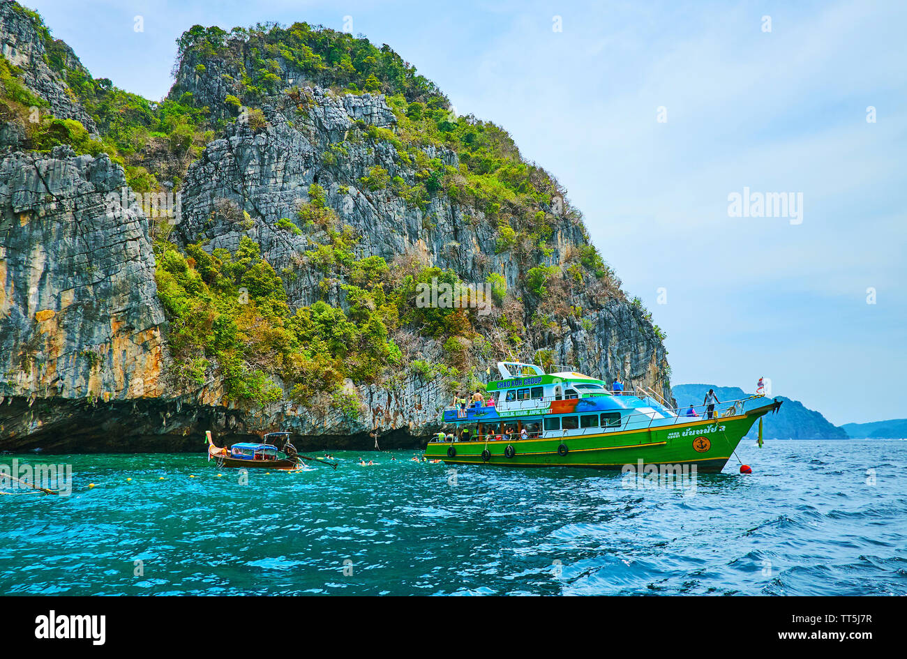 PHIPHI LEH, Tailandia - 27 Aprile 2019: la nave turistica e piccole longtail boat presso il sito di Grotta del Vichingo (Tham Phaya Nak), situato sotto il tall cl Foto Stock