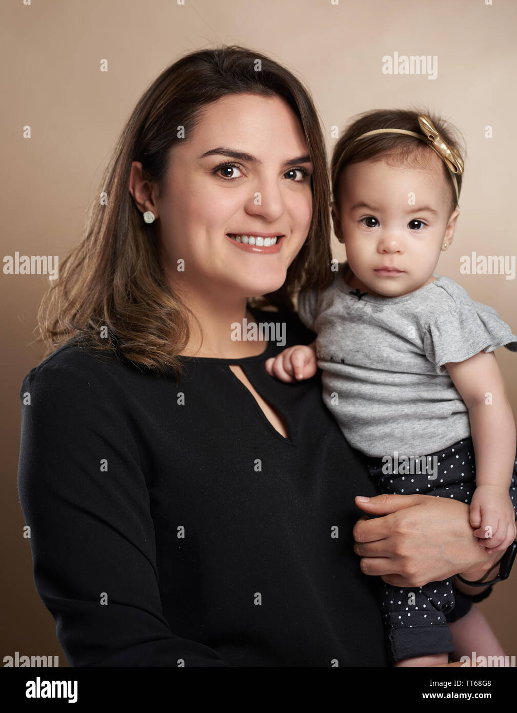 Mom holding toddler girl in studio marrone colore di sfondo Foto Stock