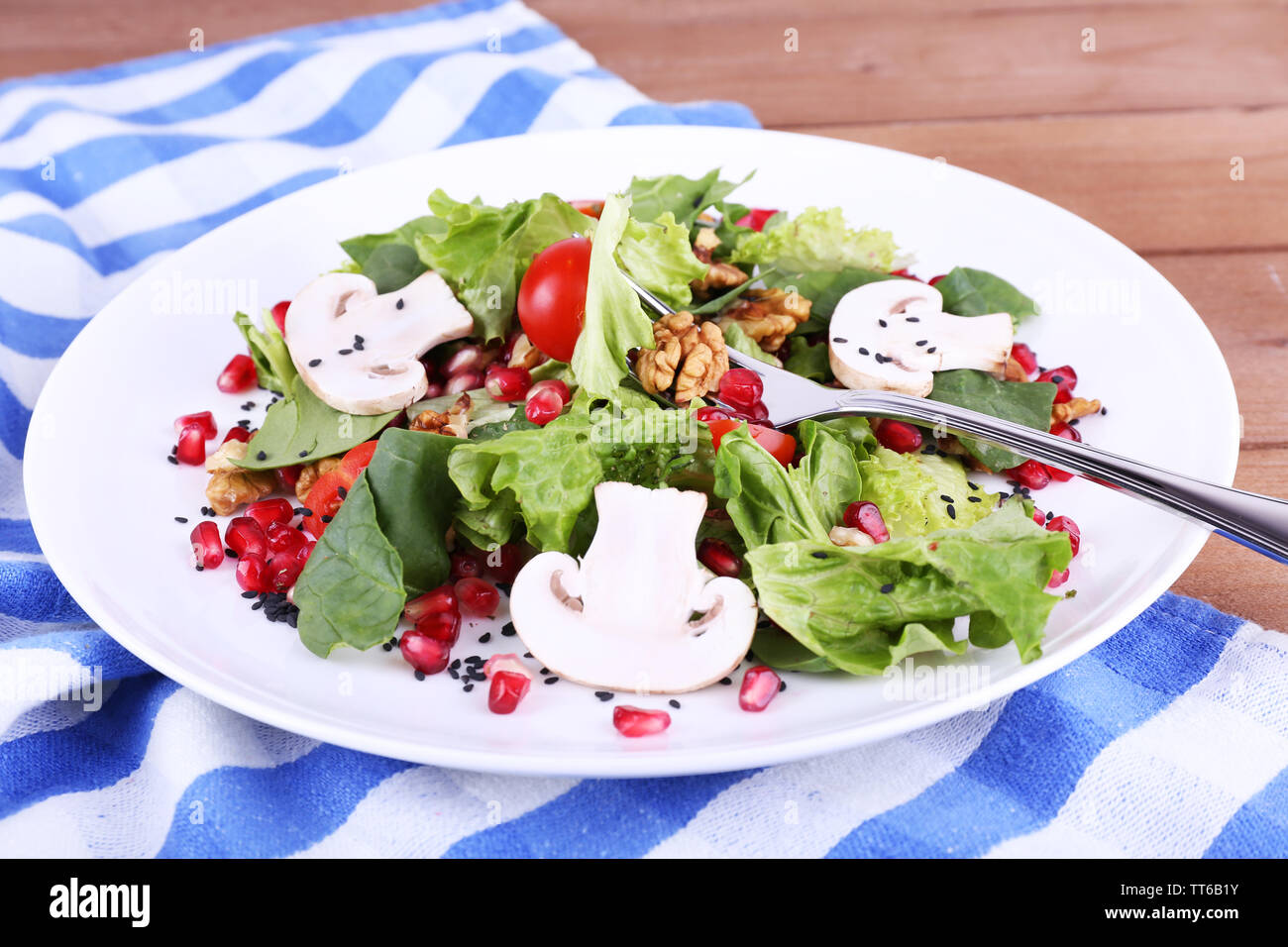 Insalata fresca con verdi, granato e spezie su lastra sul tavolo di close-up Foto Stock