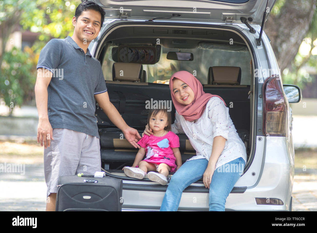 Giovane famiglia musulmana , dei trasporti, di svago, di viaggio e di persone concetto - uomo felice, donna e bambina seduta sul tronco della berlina auto e talkin Foto Stock