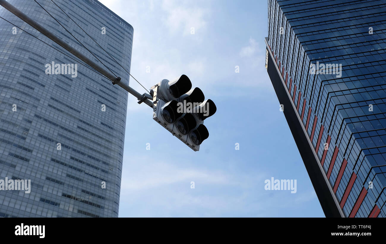 Tokyo, Giappone - 13 Maggio 2019: un semaforo con due alti edifici in background. Guardando a un angolo verso l'alto. Foto Stock