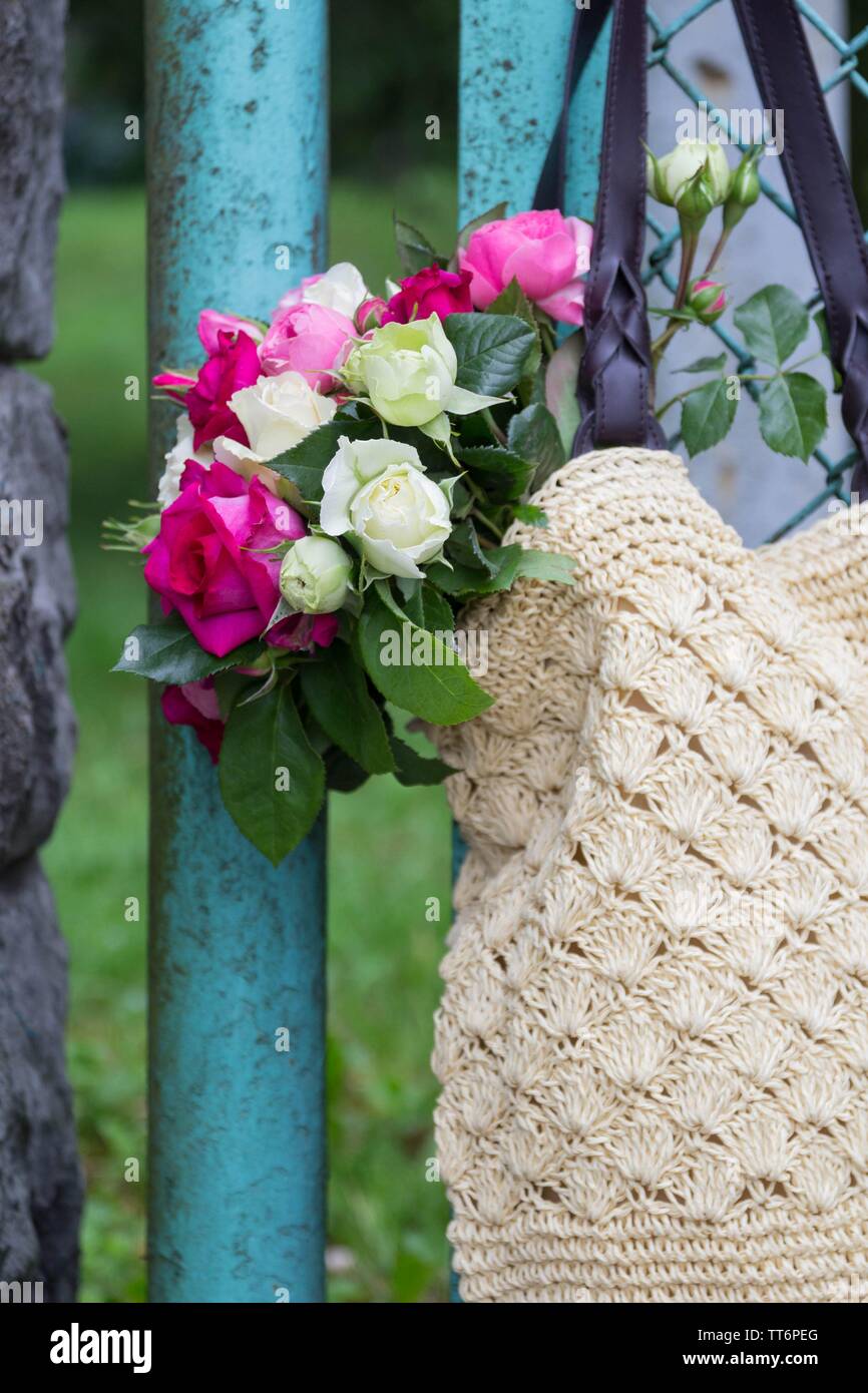 Bouquet di fragrante rosa Inglese e rose bianche in una borsa di rafia appesa alla recinzione Foto Stock