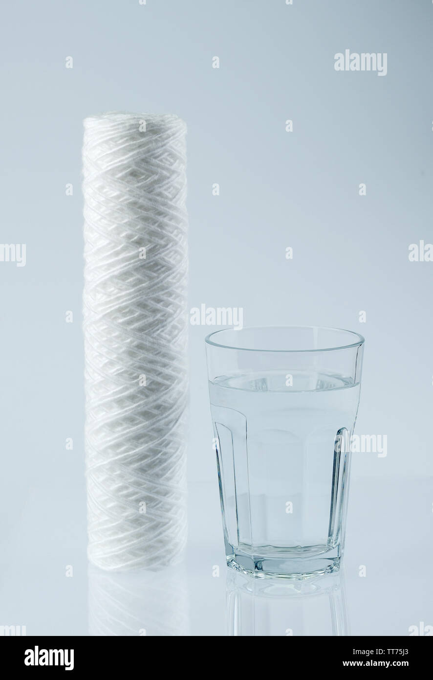 Il nuovo filtro a cartuccia per acqua e un bicchiere di acqua potabile pulita sul tavolo . Nuovo filtro per acqua di pulizia,il processo di purificazione. Foto Stock