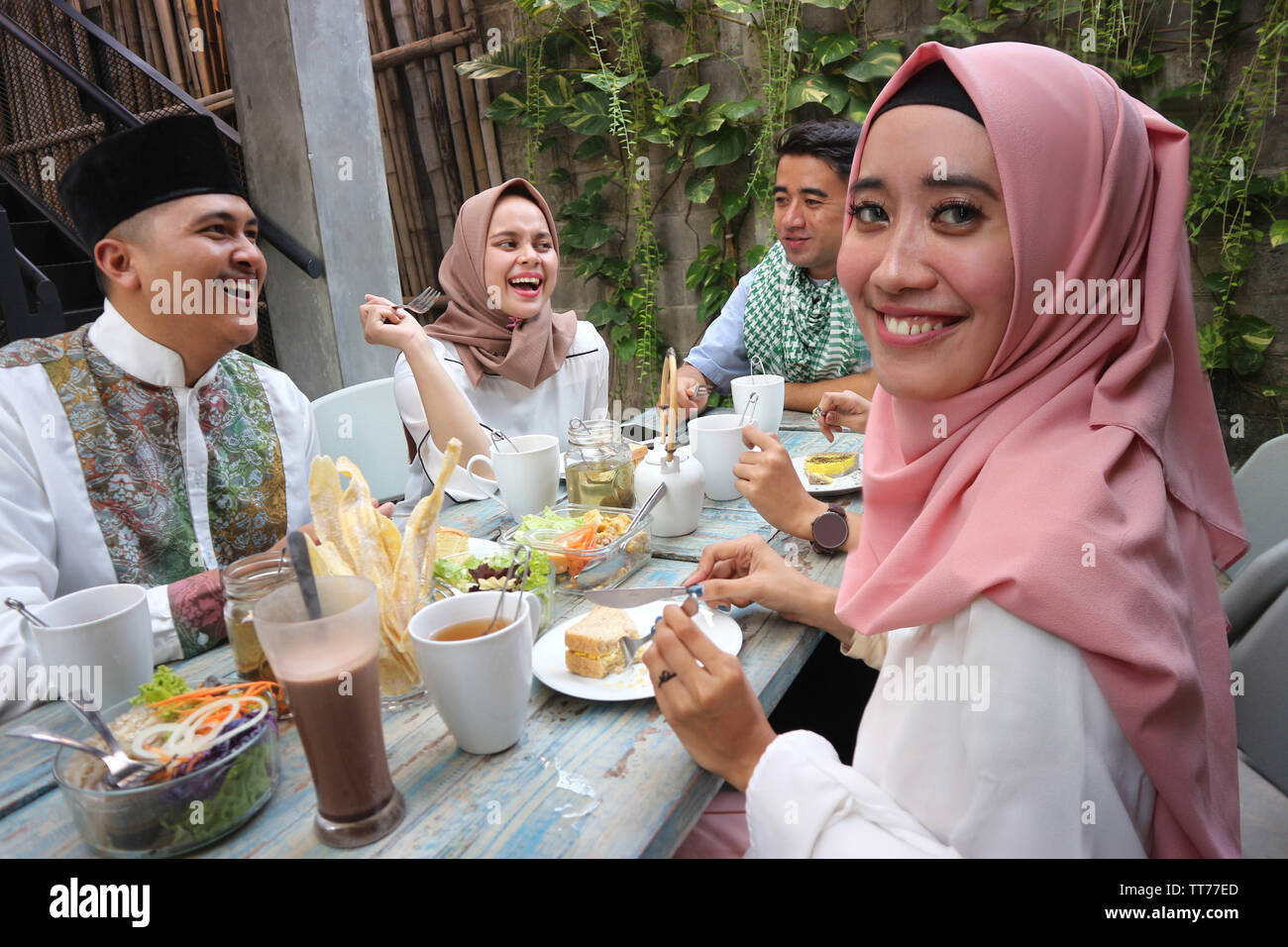 Il Portrait di giovani musulmani donna che guarda la fotocamera mentre altri pople mangiare durante il ramadan celebrazione, rompere il digiuno Foto Stock