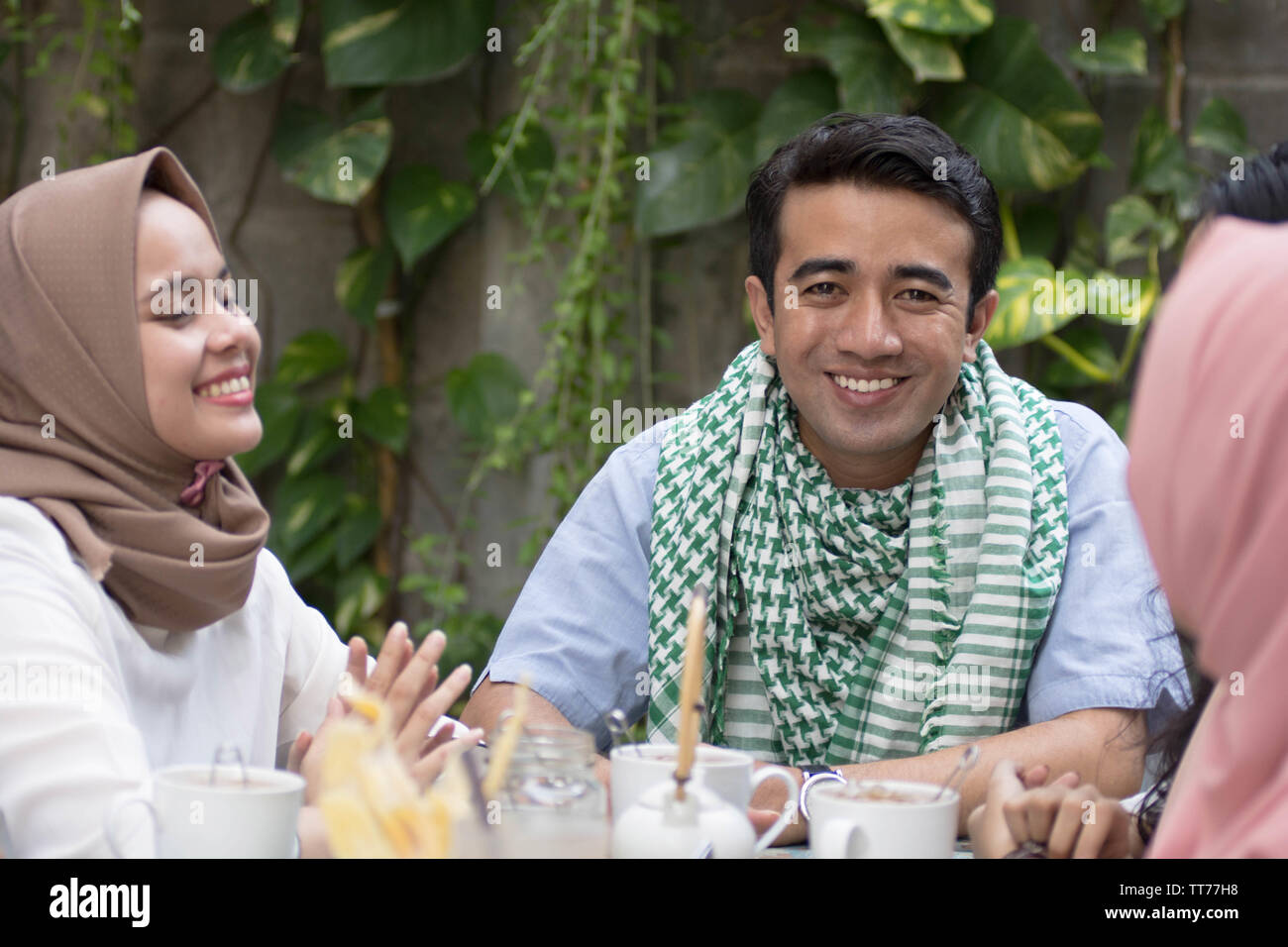 Bel uomo musulmano sorriso alla telecamera a tavola con pranzo amico sorridente durante il ramadan celebrazione, rompere il digiuno Foto Stock