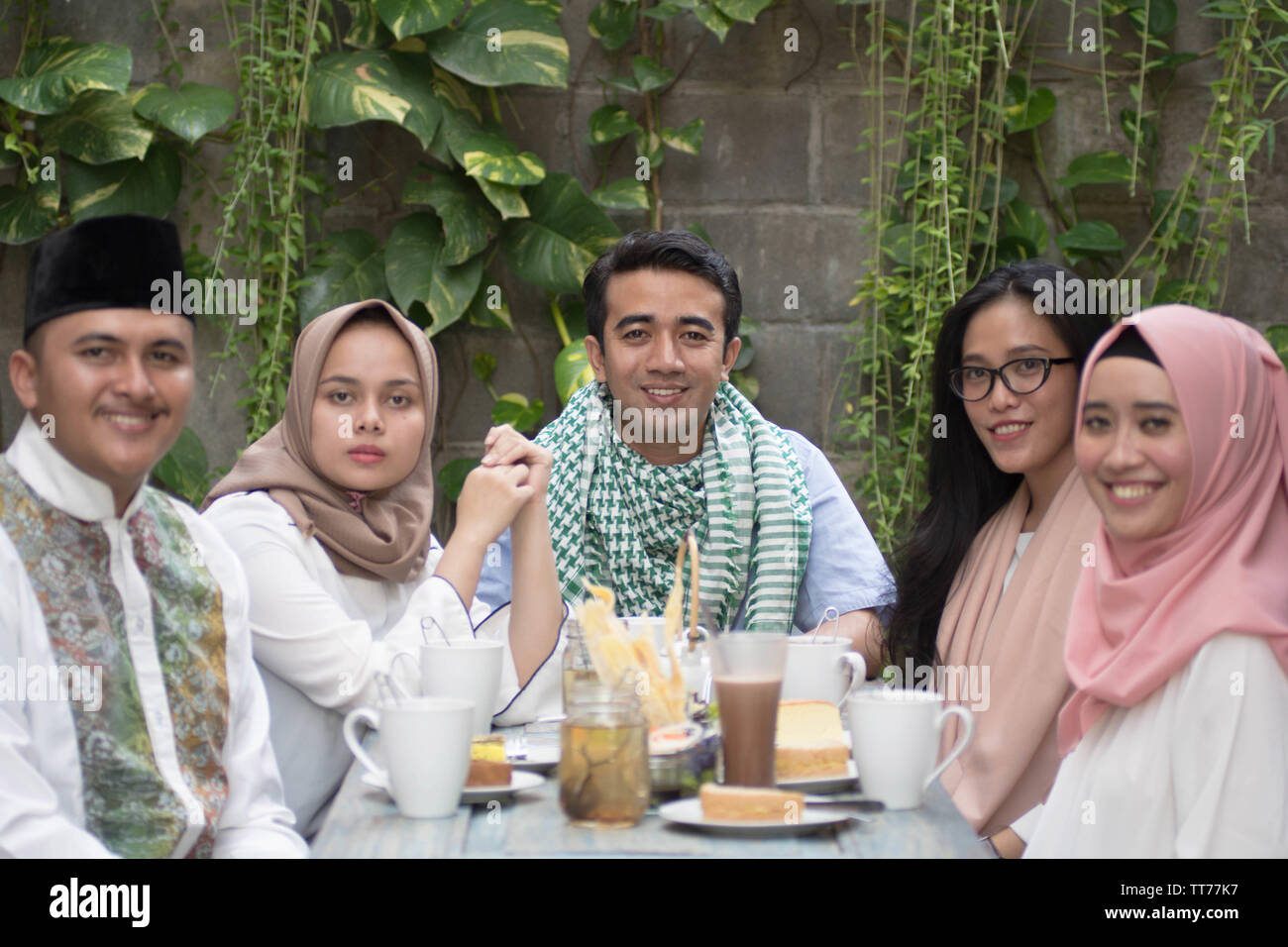 Gruppo di felice giovani musulmani di consumare la cena all'aperto cercando di telecamera durante il ramadan celebrazione, rompere il digiuno Foto Stock