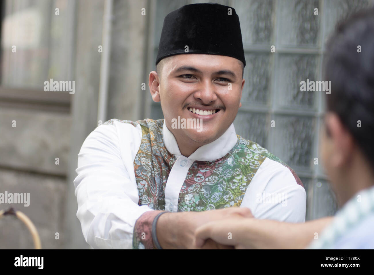 Due uomo avente il tremolio delle mani al tavolo da pranzo durante la pausa del pranzo e cena durante il ramadan celebrazione, rompere il digiuno Foto Stock