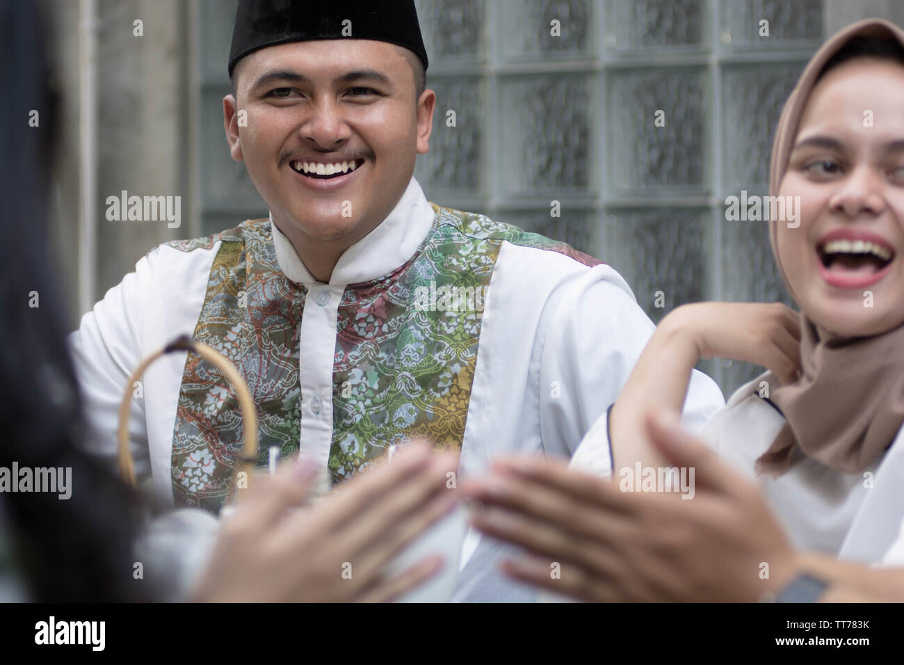 Musulmani l uomo e la donna sorridere e ridere mentre avente saluto al tavolo da pranzo durante la pausa del pranzo e cena durante il ramadan celebrazione, rompere il digiuno Foto Stock