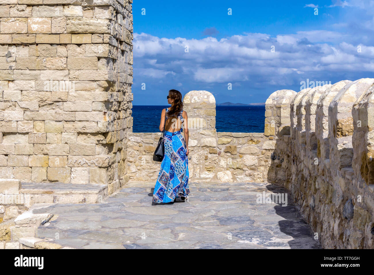 La città di Heraklion, Creta / Grecia. Donna in vestito blu godendo la vista panoramica del mare di Creta dal tetto della fortezza Koules Foto Stock