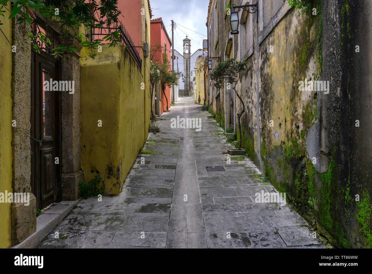 Archanes, isola di Creta / Grecia. Stretto vicolo lastricato, Archanes Village che conduce ad una chiesa con vecchie case tradizionali con moss sulle loro pareti Foto Stock