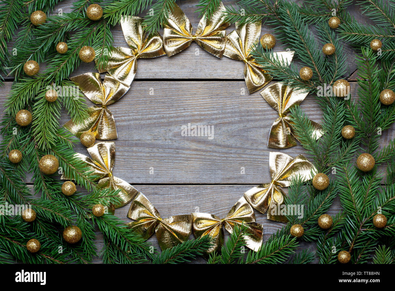 Scheda di Natale concetto con abete rami, globuli di brocade e un cerchio di centine d'oro su sfondo di legno - Spazio di testo Foto Stock