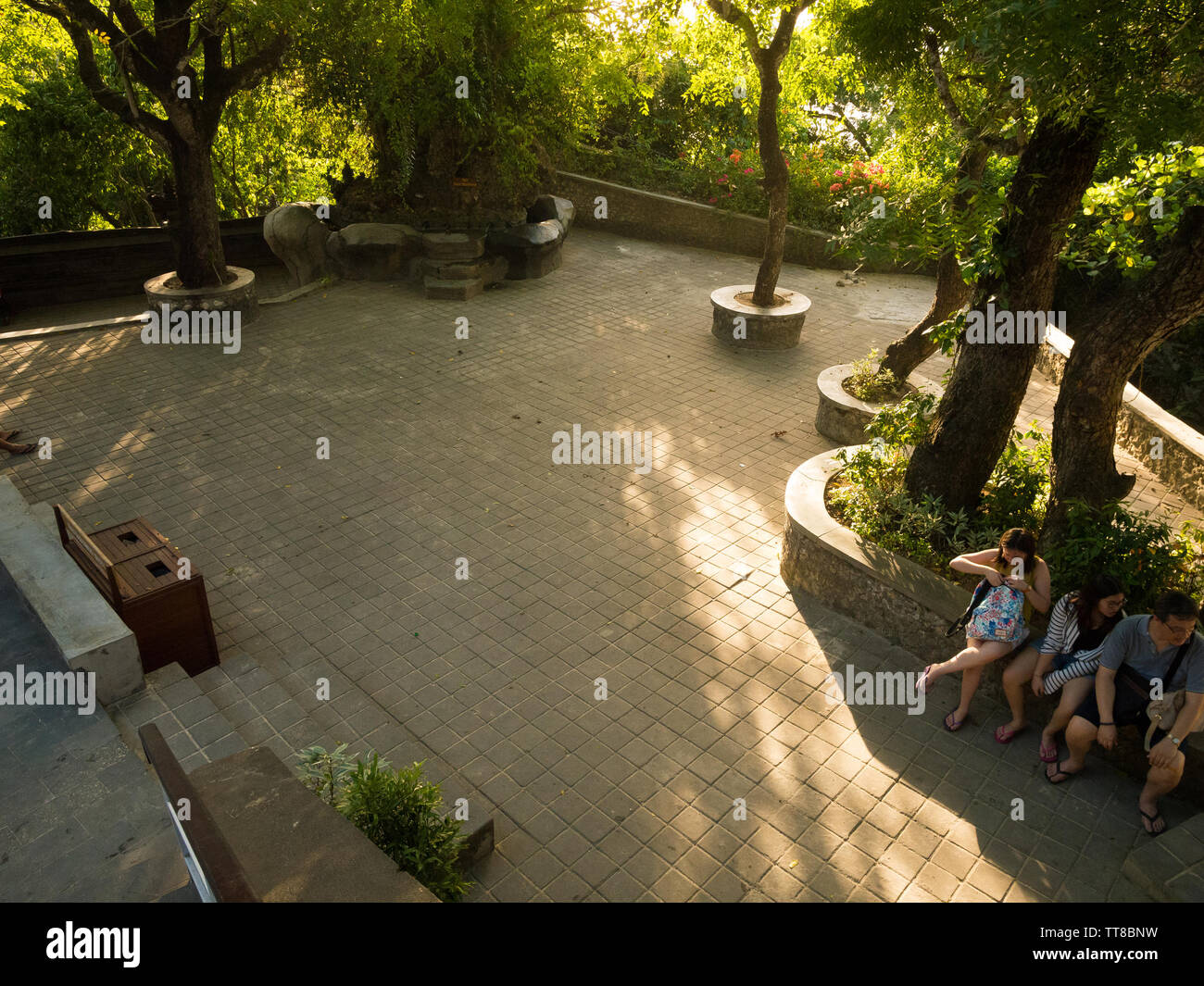 I turisti sedersi e rilassarsi in ombra in un cortile piastrellato da Padang Padang spiaggia di Bali, Indonesia. Foto Stock