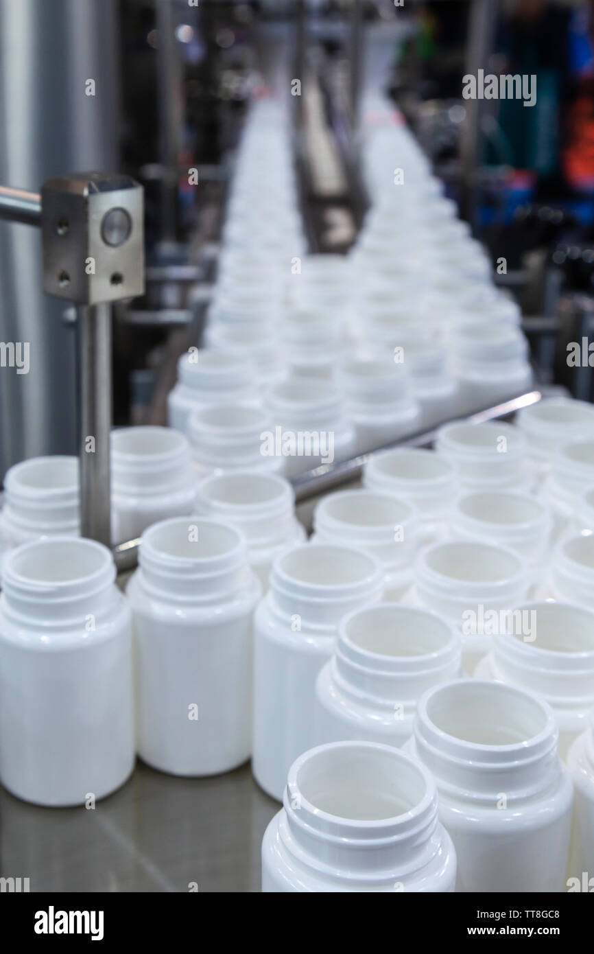 Bottiglia di plastica bianca sulla linea di produzione del nastro alla macchina di riempimento in fabbrica. Il fuoco selettivo. Foto Stock
