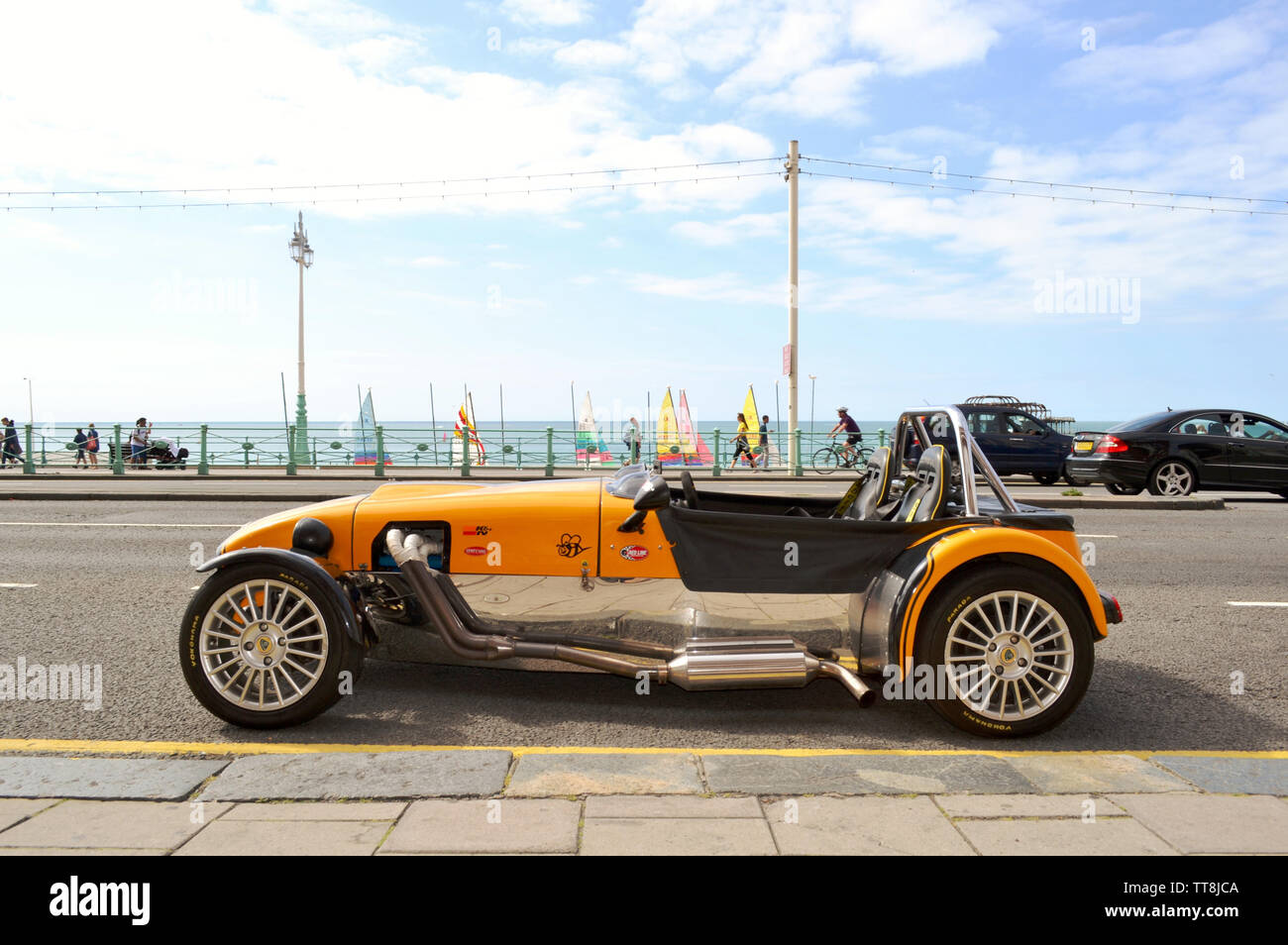 Brighton, Regno Unito - 14 agosto 2016: bel giallo vintage Lotus Cobra auto parcheggiate nella spiaggia di Brighton avenue con resti di Brighton il vecchio molo Ovest. Foto Stock