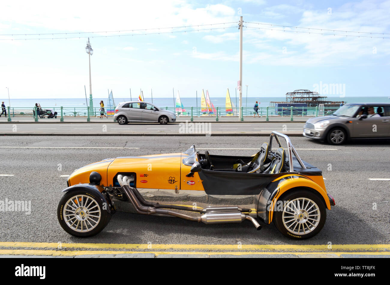 Brighton, Regno Unito - 14 agosto 2016: bel giallo vintage Lotus Cobra auto parcheggiate nella spiaggia di Brighton avenue con resti di Brighton il vecchio molo Ovest. Foto Stock