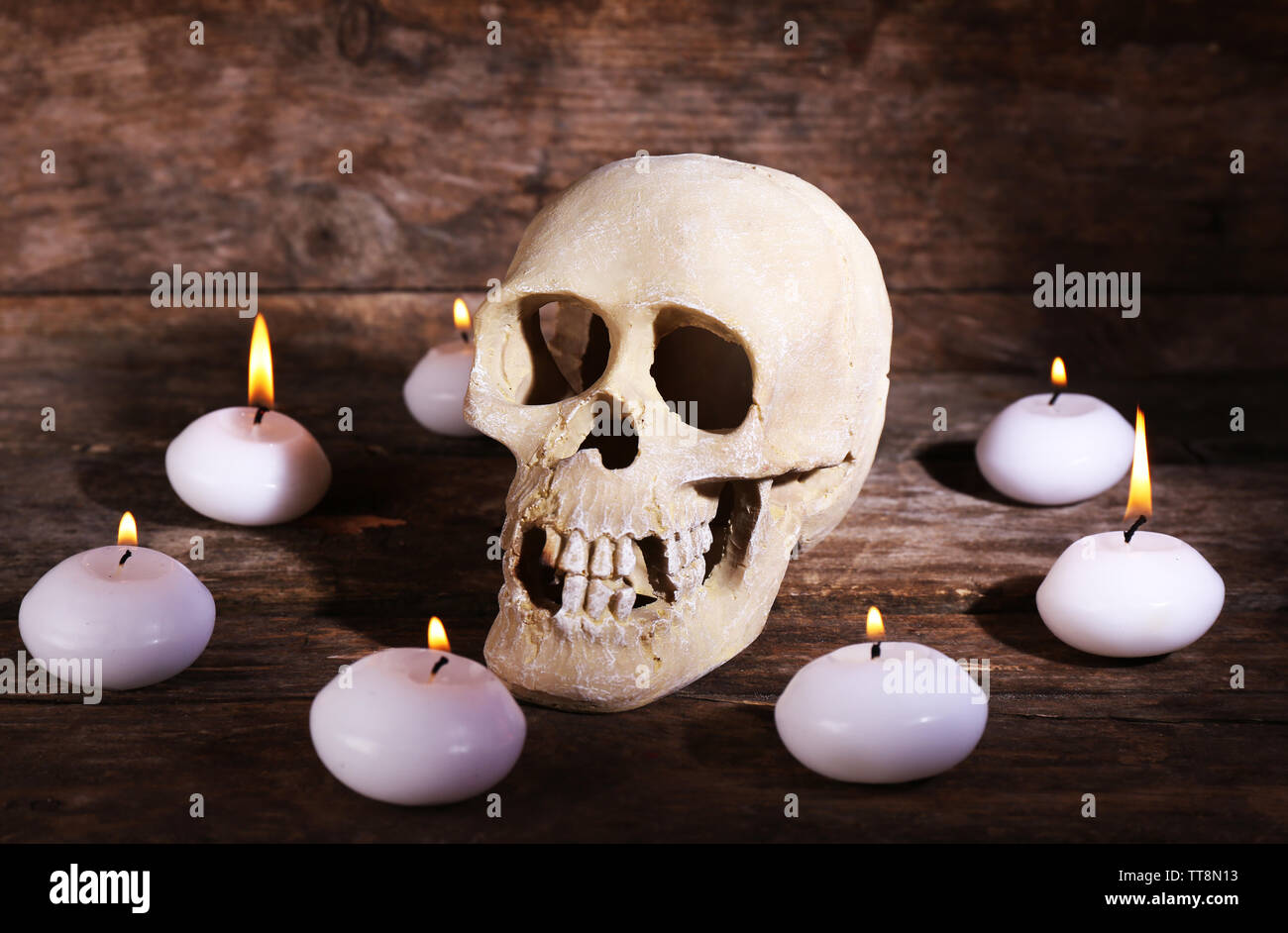 Natura morta con teschio umano e candele su sfondo di legno Foto Stock