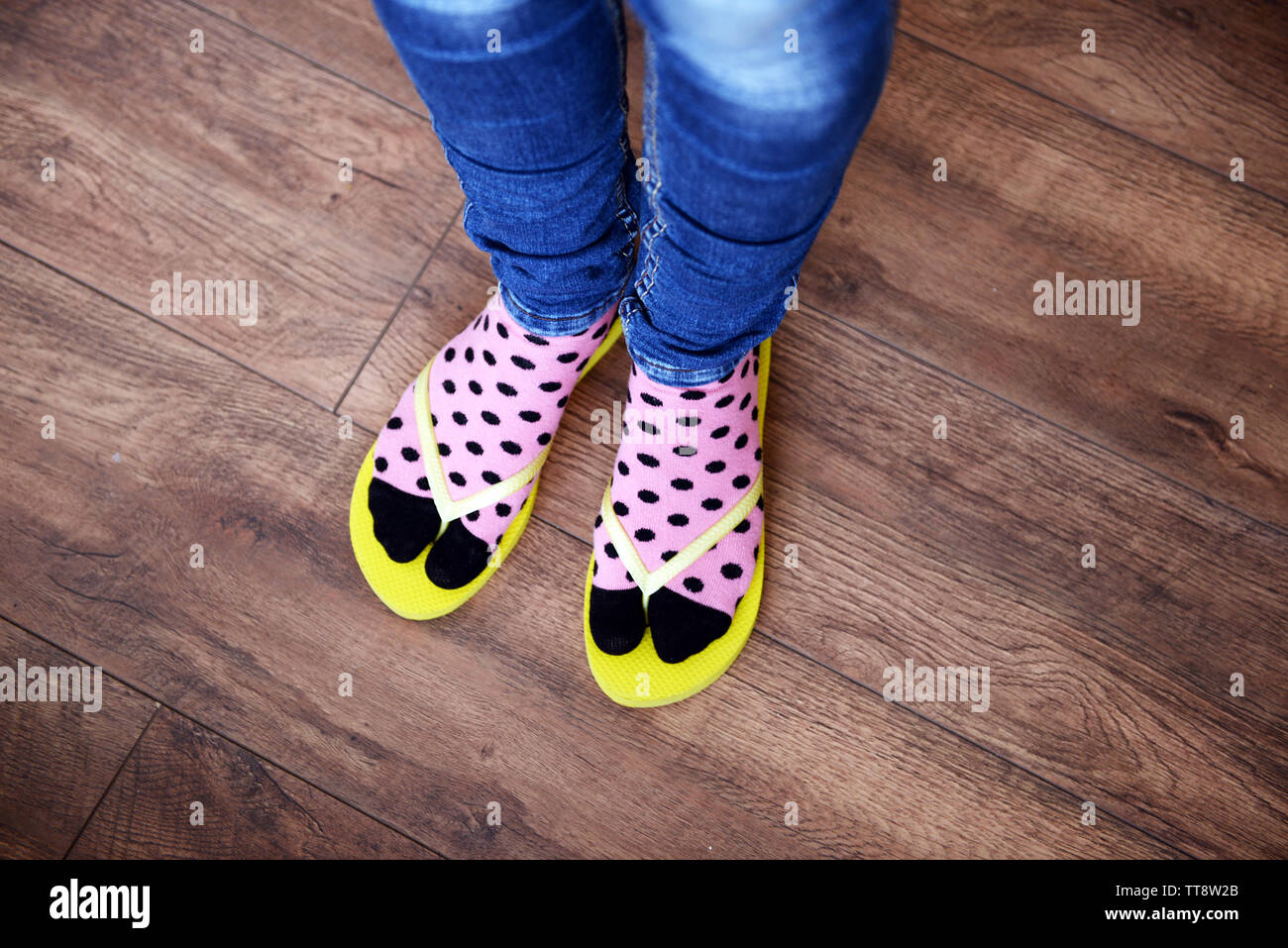 I piedi femminili in calze con rosa flip-flop, su sfondo a pavimento Foto Stock