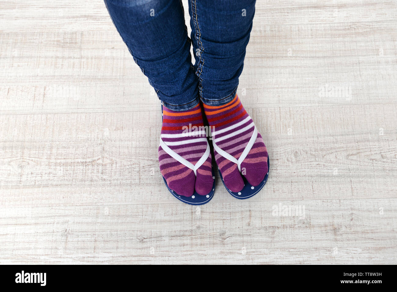 I piedi femminili in calze con rosa flip-flop, su sfondo a pavimento Foto Stock