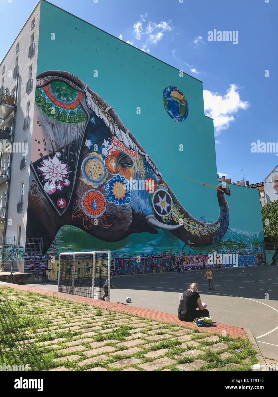 Berlino, Germania - Giugno 2019: giochi per bambini all'aperto sul parco giochi di calcio su strada con graffiti murale in background a Berlino Kreuzberg Foto Stock
