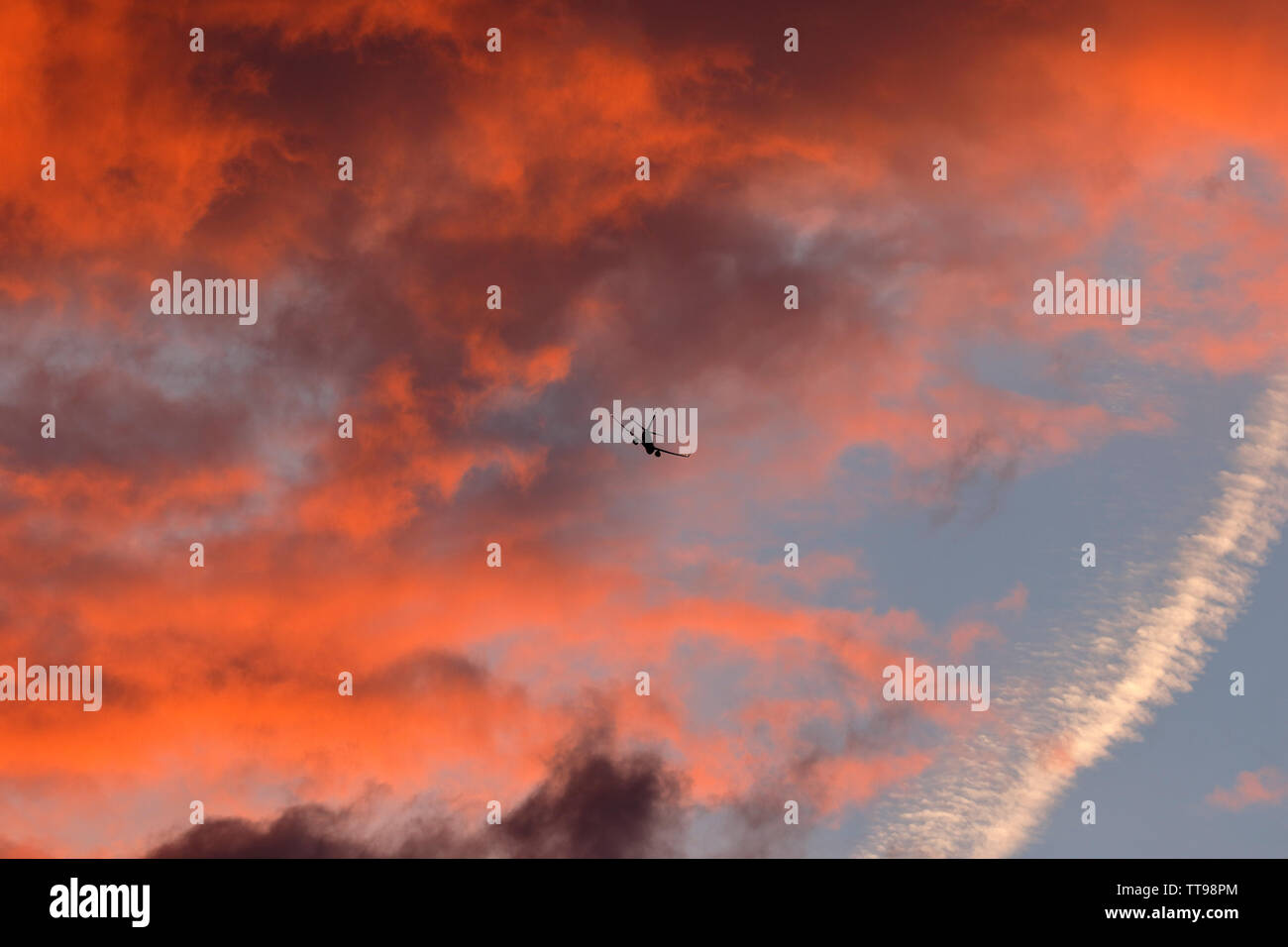 Sunset cloudscape mostra nuvole grigie e i colori del sole che è sotto l'orizzonte. Oltre a un aereo di linea in partenza dall'aeroporto di Stansted Essex Foto Stock