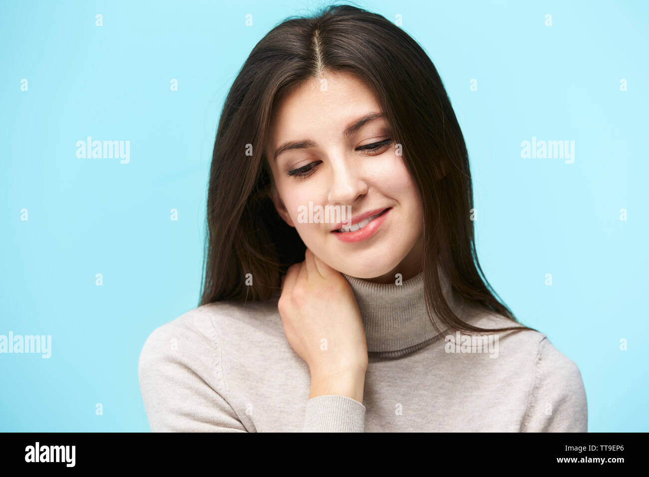 Ritratto di una giovane e bella donna caucasica, felice e sorridente a occhi chiusi isolati su sfondo blu Foto Stock