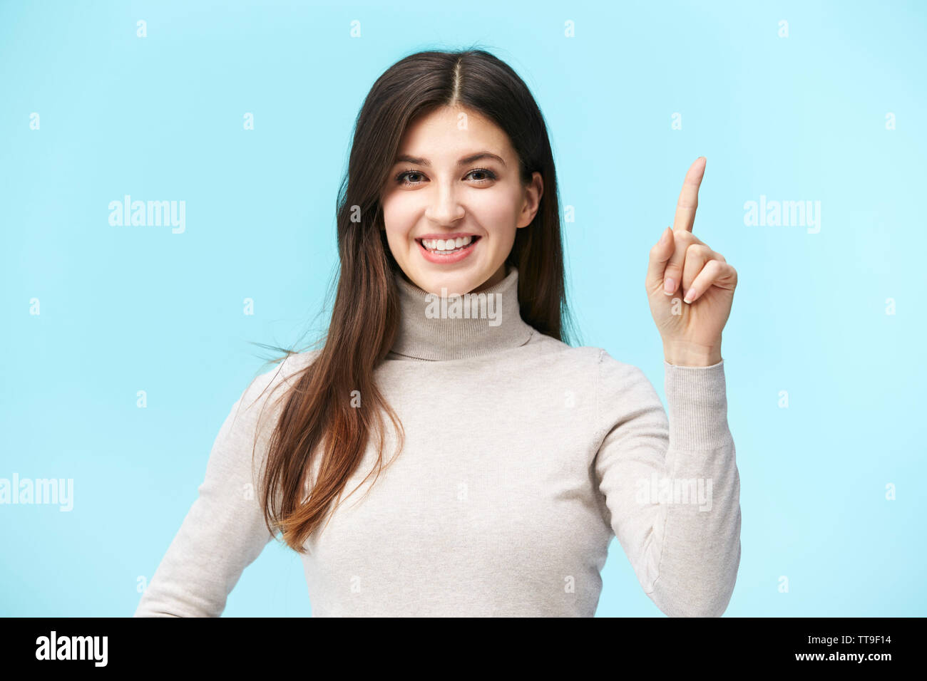 Bellissima giovane donna caucasica che mostra un numero uno segno, guardando la telecamera sorridendo, isolato su sfondo blu Foto Stock