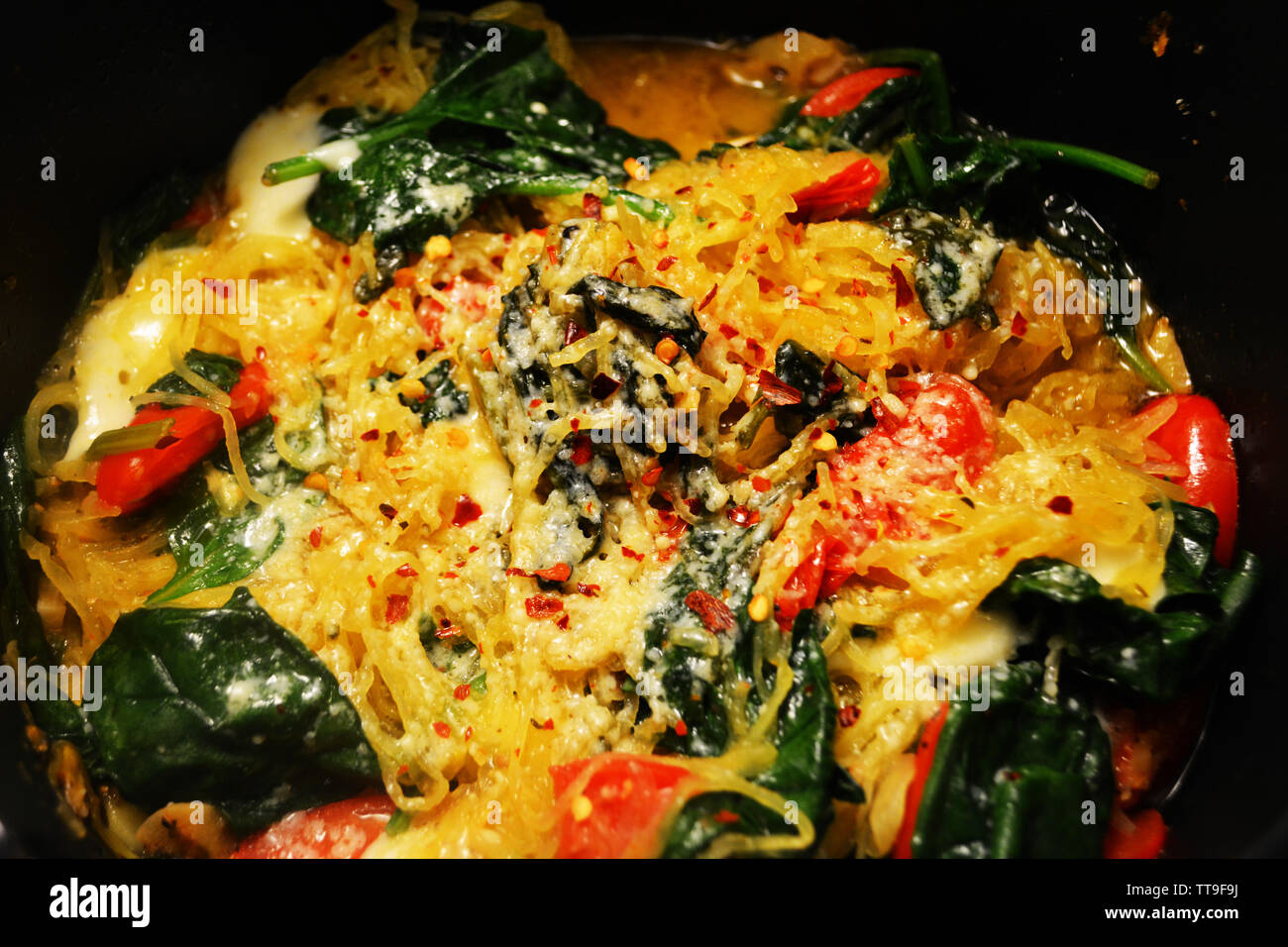 Grande porzione di spaghetti Squash in una ciotola con gli spinaci sole asciugato il pomodoro, la mozzarella, e le erbe e spezie Foto Stock