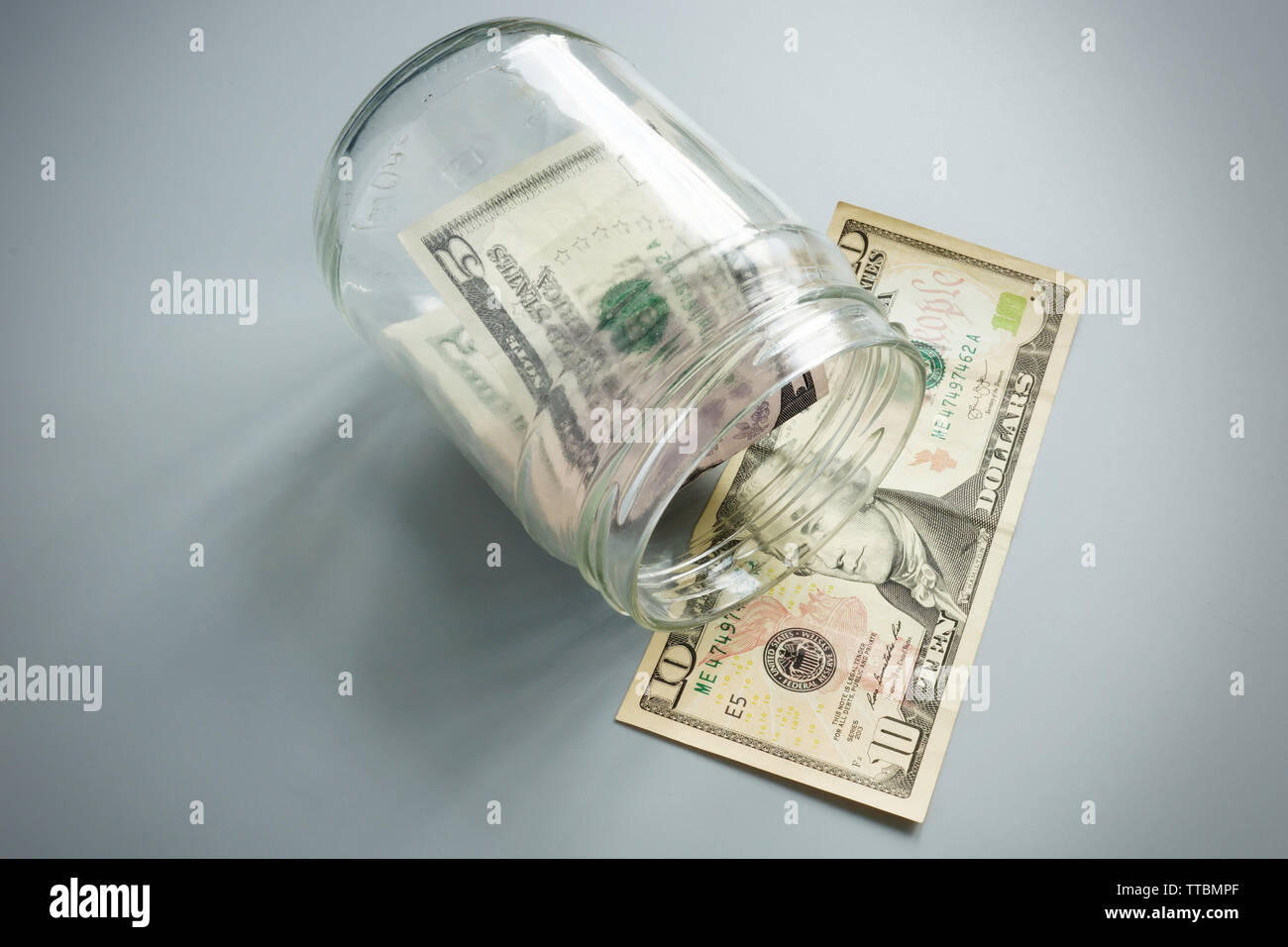 Fallimento o insolvenza e problemi con il denaro. Vaso di vetro con pochi dollari di banconote. Foto Stock
