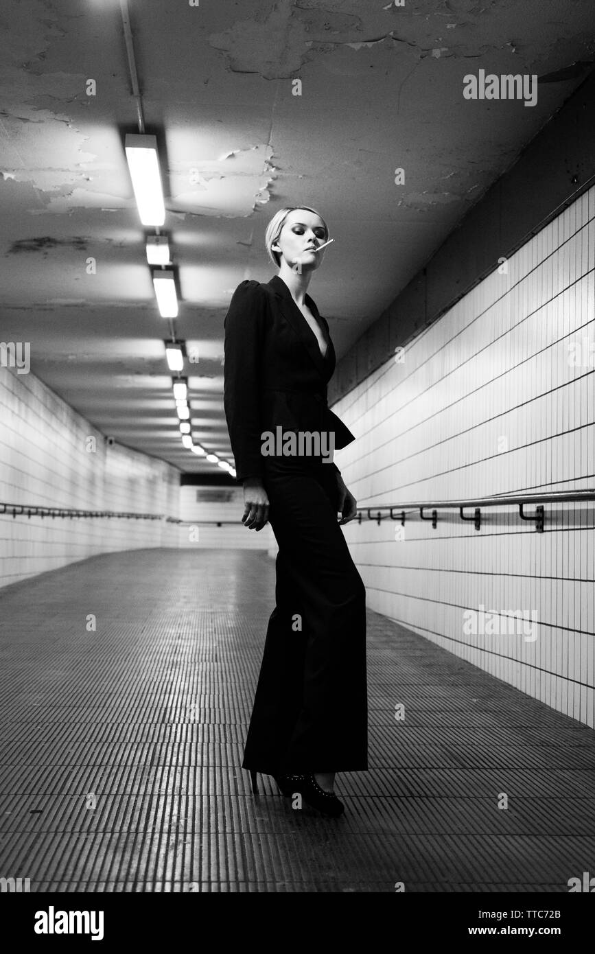 Donna bionda in abito nero in una stazione della metropolitana Foto Stock