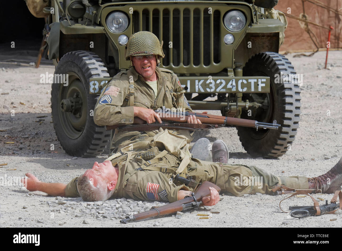 Reenactor vestito come un soldato dell'esercito statunitense ottantaduesima Airborne "tutti Americani" seduto di fronte a una Jeep Foto Stock