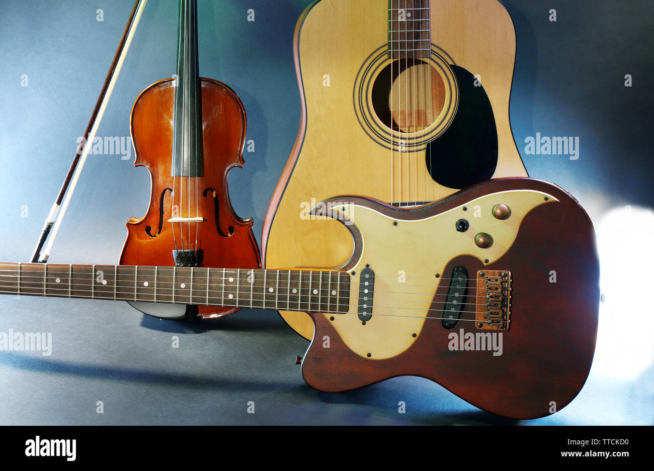 Elettrico e chitarre acustiche, violino su sfondo blu Foto Stock