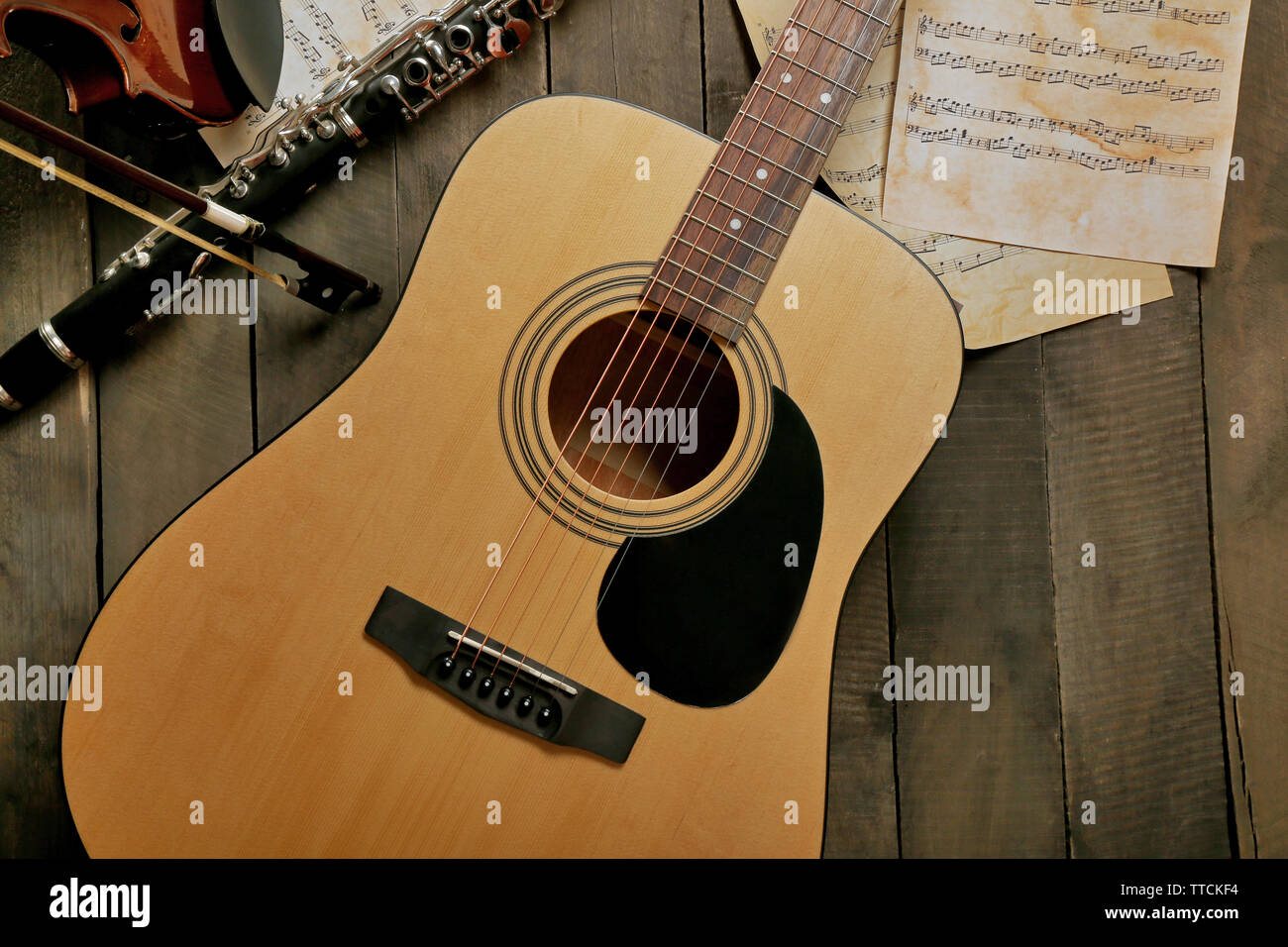 Chitarra acustica, sassofono soprano, violino, flauto e fogli di appunti su sfondo di legno Foto Stock