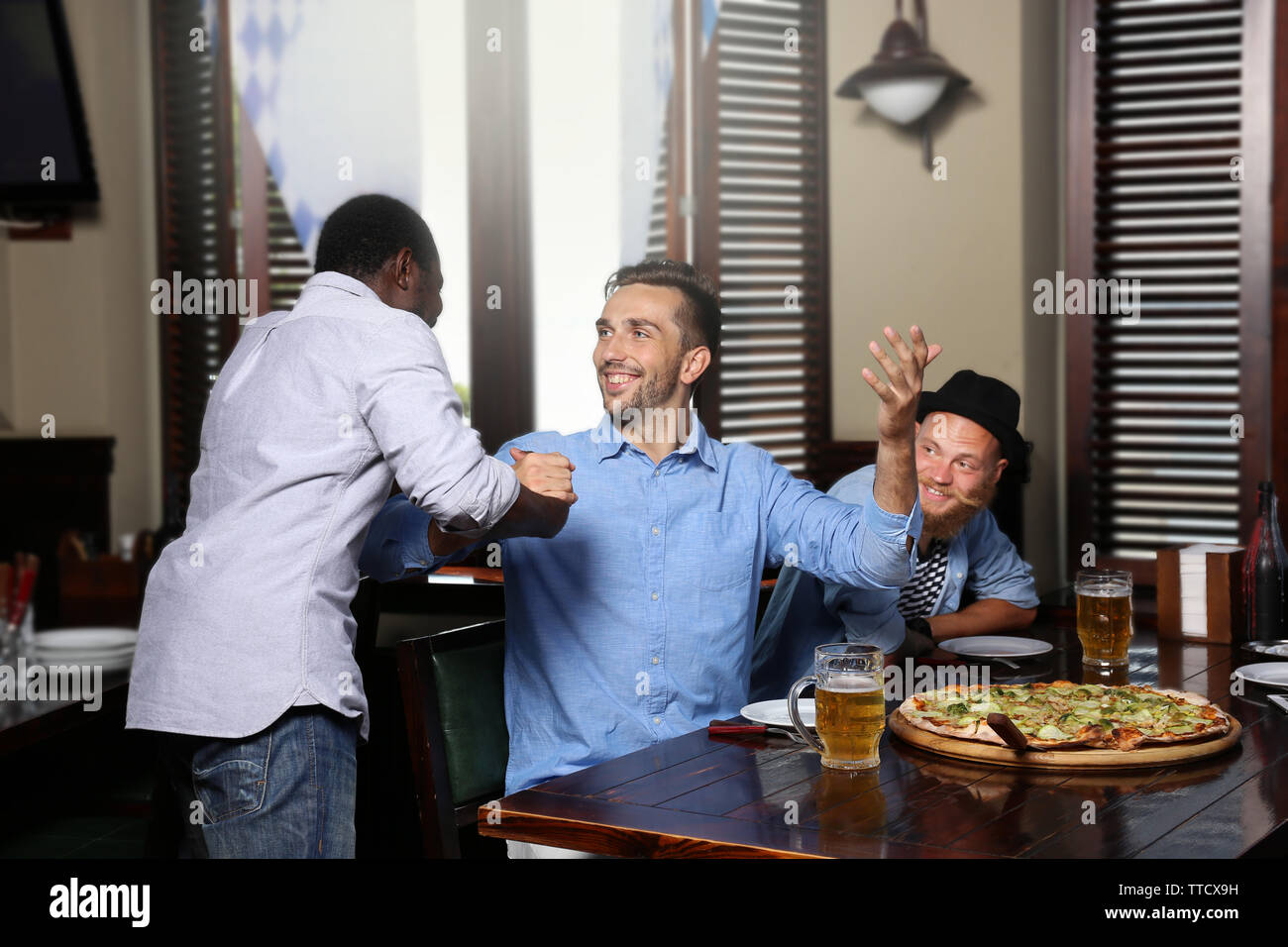 I giovani uomini a bere birra e parlare in cafe Foto Stock