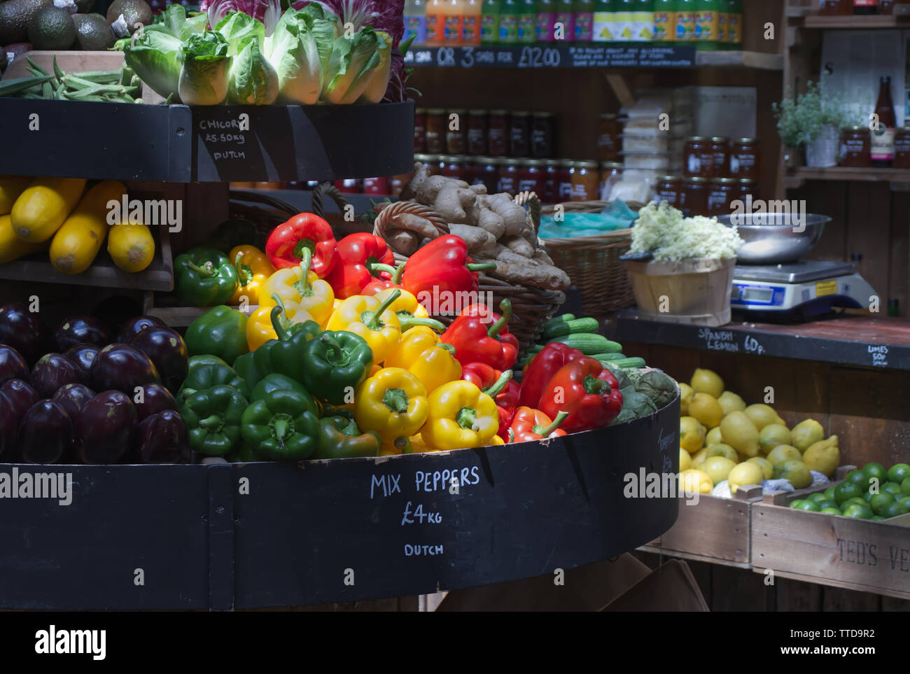 Un display di verdure su un mercato sgabello, peperoni principalmente evidenziato da un fascio di luce solare Foto Stock